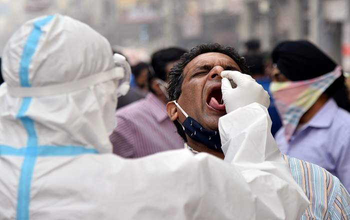 A health worker in personal protective equipment (PPE) collects a swab sample from a man in Delhi (Image credit: Business Standard)