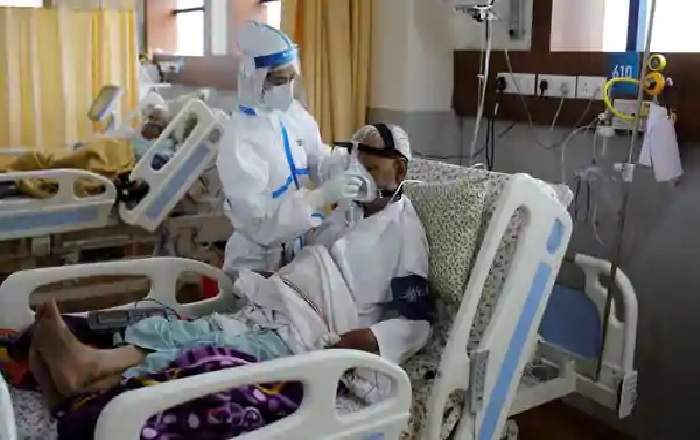 A medical worker takes care of a patient suffering from COVID-19 at a hospital in Noida (Image credit: Mint)
