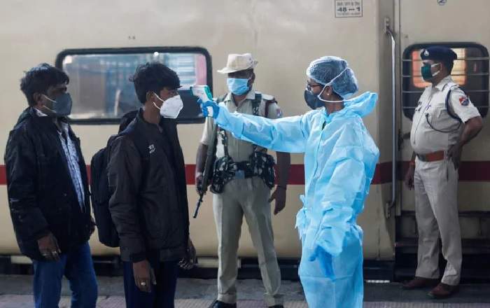 A health worker checking a passenger's temperature at a railway station (Image credit: NDTV)
