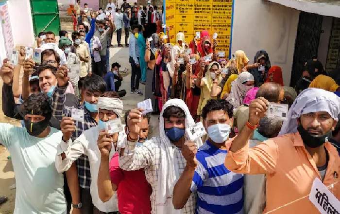 People show their voter ID as they stand in queue to cast their vote for Uttar Pradesh Panchayat election in Agra (Image credit: News18)
